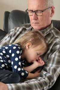 Older man sleeping with a young girl asleep on his lap